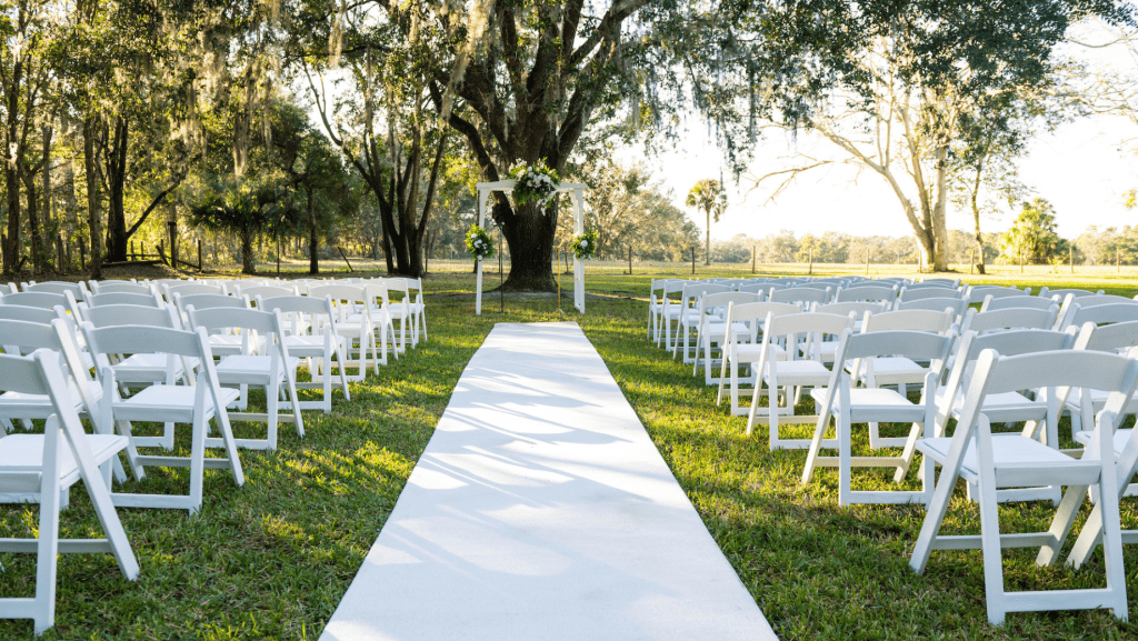White chivarri wedding chairs placed beside a white walkway to a wedding arch
