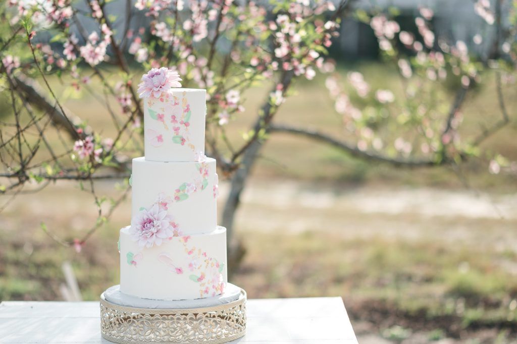 Spring floral frosting decorations along a simple, white, 3-tiered wedding cake