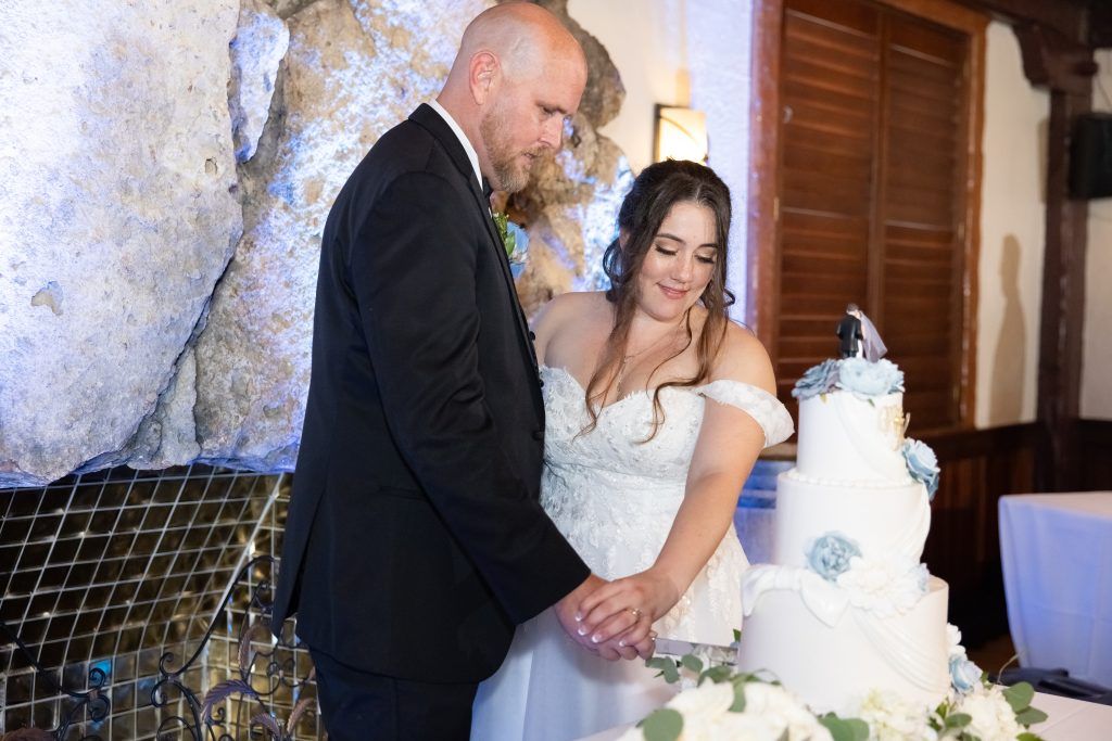 white and dusty blue wedding cake being cut by bride and groom in Orlando, Florida