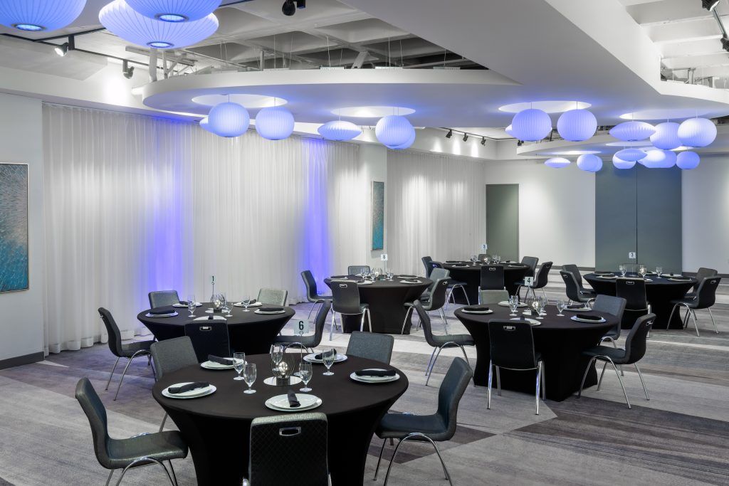 Elegant event space at Aloft Orlando Downtown set with round tables and blue accent lighting, perfect for Central Florida wedding venue reception