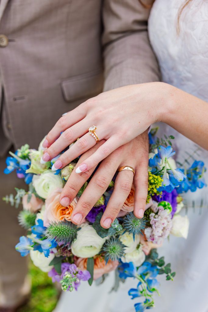 Brides hand draped on grooms hand placed on top of the bridal bouquet
