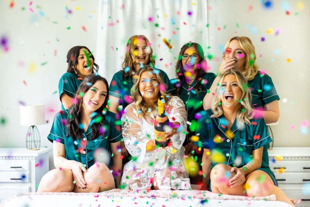 bride and bridesmaids smiling and laughing while confetti falls