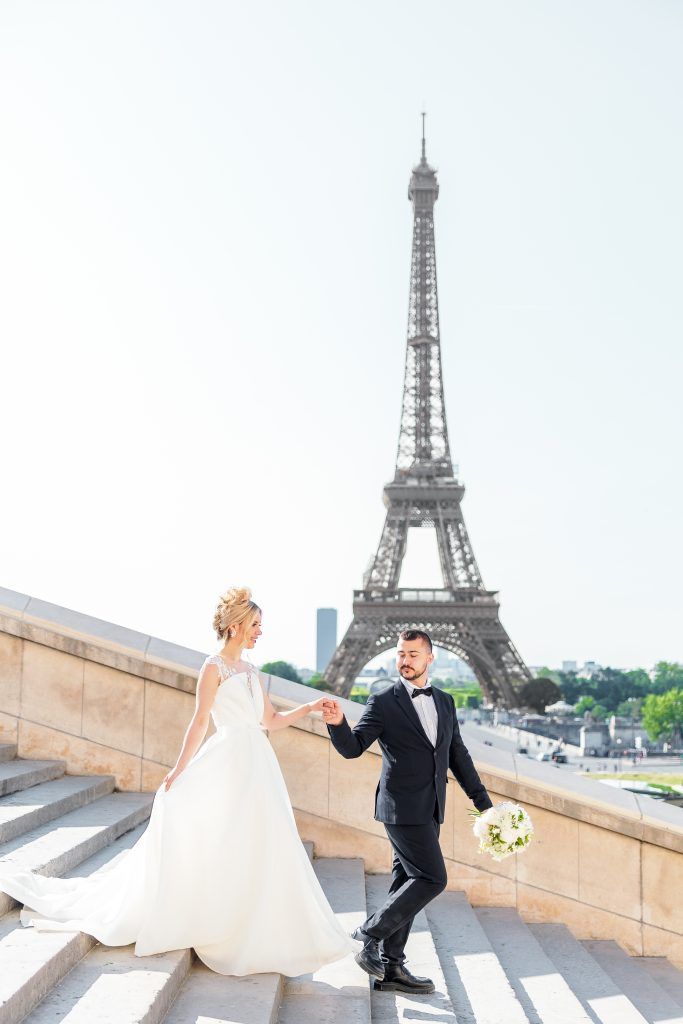 bride and groom holding hands as groom leads bride down stairs in Paris, France