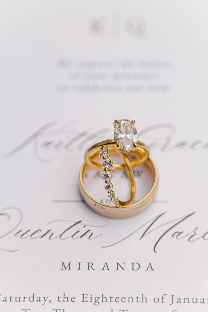 close up shot of wedding band and rings on wedding stationary