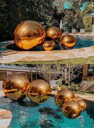 Giant, shiny gold balloons place and floating in a pool
