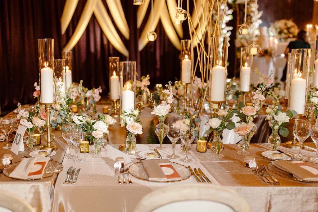 Elegant wedding reception with mahogany chiavari chairs, round tables draped in white linens, classic white floral centerpieces, and romantic candlelight.