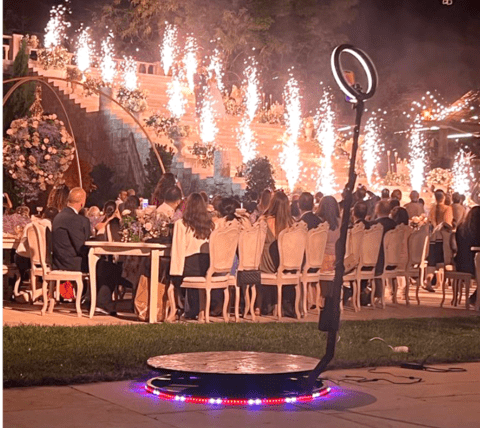 wedding fireworks in the background with guests watching seated behind a 360 selfie stand