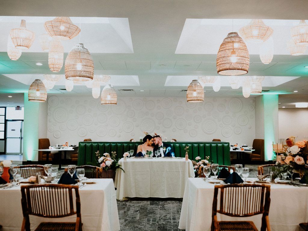 Bride and groom sit at a sweetheart table in a modern dining space at DoubleTree by Hilton Orlando, surrounded by floral décor.