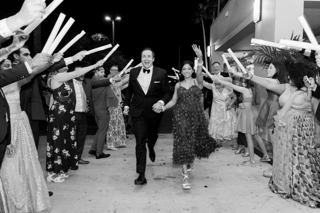 Newlyweds make a joyful nighttime exit as guests cheer them on outside DoubleTree by Hilton Orlando.