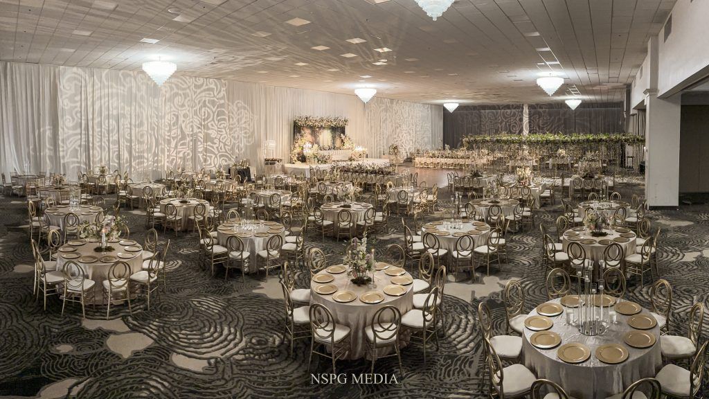 Elegant ballroom setup at DoubleTree by Hilton Orlando featuring gold chairs, floral centerpieces, and a romantic stage backdrop.