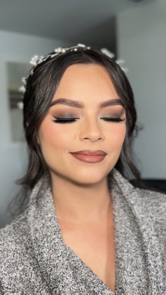 Bride featuring winged eyeliner, neutral eyeshadow, and matte nude lipstick, smiling with eyes closed.