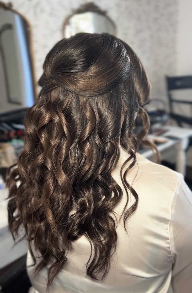 Dark brown hair styled in loose, defined curls with a smooth half-up twist at the crown.
