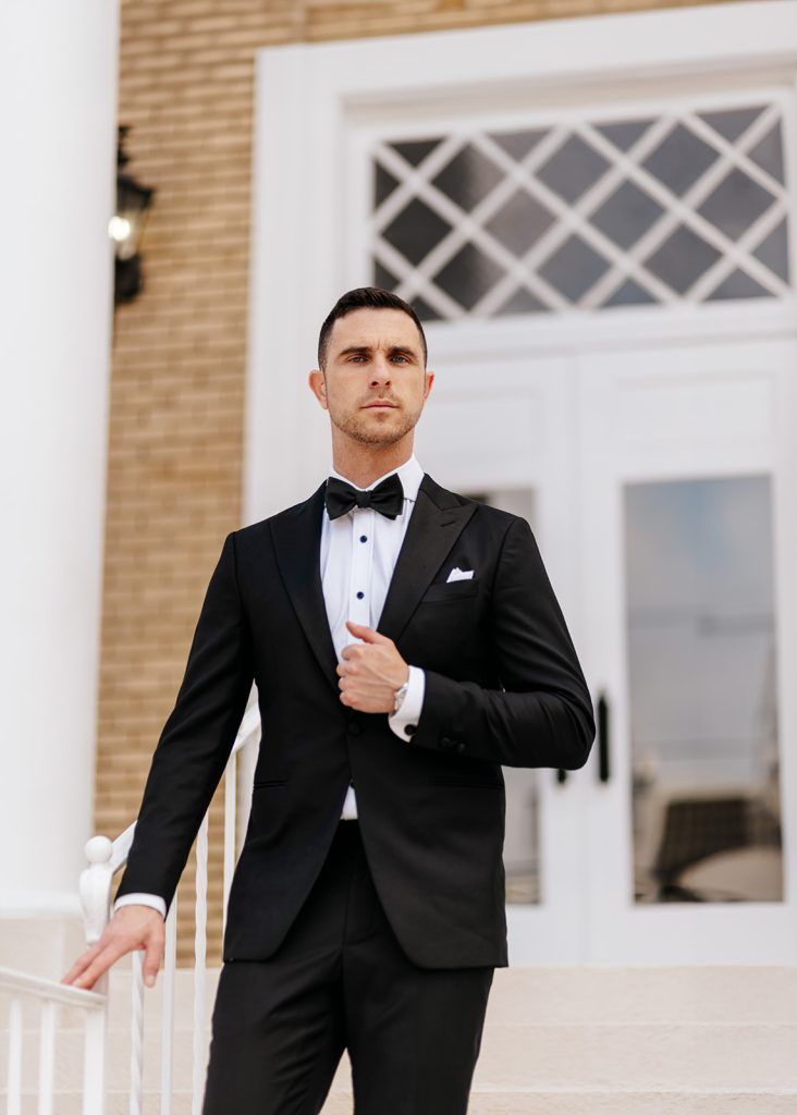 man wearing a traditional black suit with a white undershirt and black bowtie